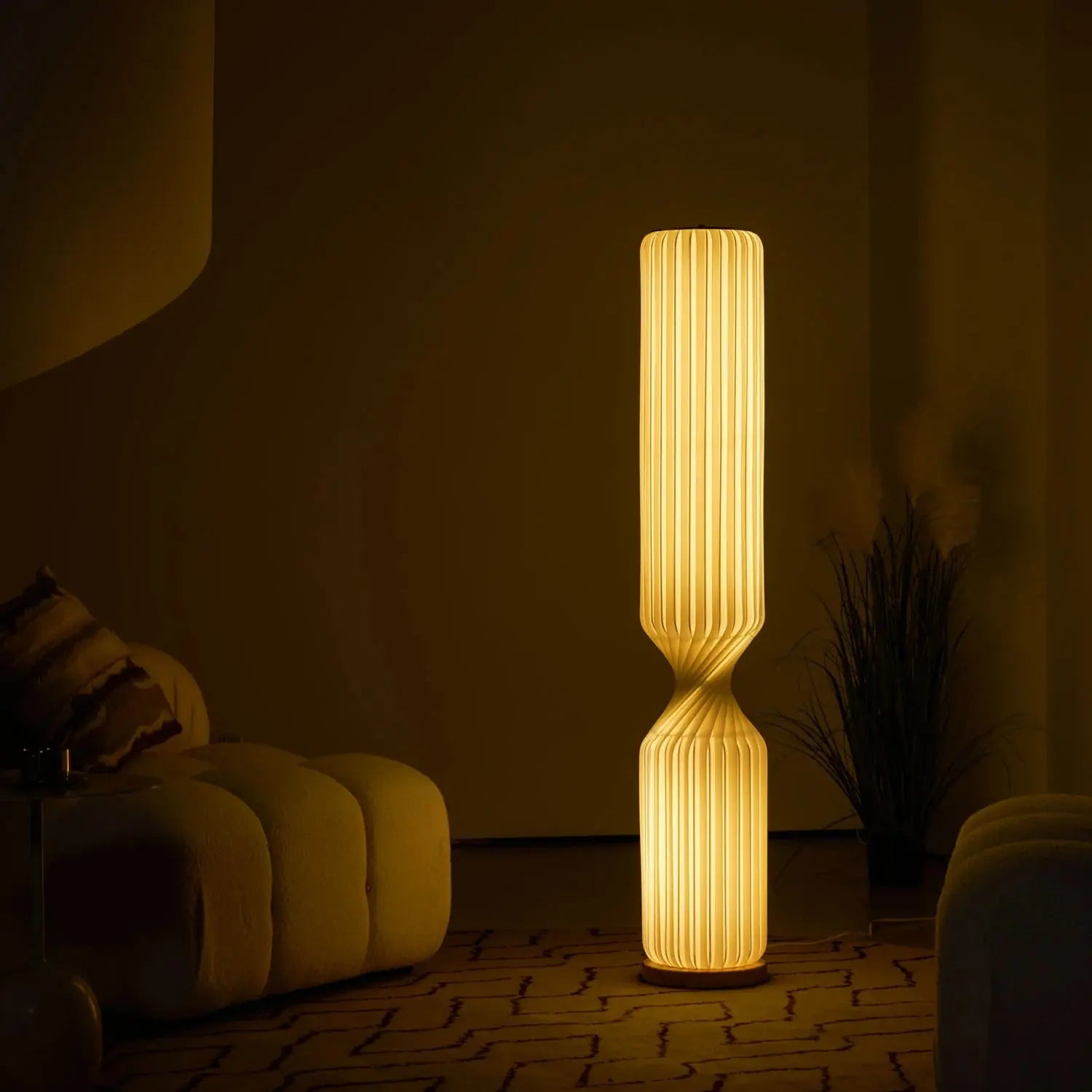 Solenne sculptural floor lamp glowing amber in dark moody living room corner